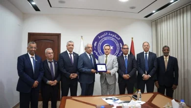 libye-comite-parlementaire-marocain-1 | MCG24 | موقع إلكتروني مغربي شامل متجدد على مدار الساعة Group of men in suits posing for a formal award ceremony, central figure holding a plaque, emblem backdrop with Arabic text behind them.