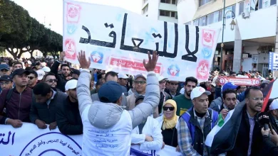 marche-enseignants-rabat32 | MCG24 | موقع إلكتروني مغربي شامل متجدد على مدار الساعة Crowd of protesters in a city street holding a large Arabic banner and smaller signs.