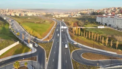 maroc-infrastructures-investissements-budget-ae832 | MCG24 | موقع إلكتروني مغربي شامل متجدد على مدار الساعة Aerial view of a multi-lane highway interchange with looping ramps, green fields on the sides and a city in the distance.
