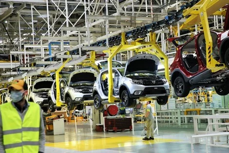 maroc_renault_voitures_613243937 | MCG24 | موقع إلكتروني مغربي شامل متجدد على مدار الساعة Car manufacturing assembly line with vehicles on an overhead conveyor and workers in high-visibility vests inspecting them in a factory.