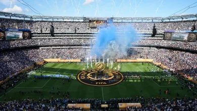 A packed soccer stadium during a trophy ceremony with blue smoke rising from the field around the FIFA Club World Cup emblem at center.
