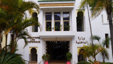 ministre-de-lInt-C3-A9rieur_png_jpg-1jpg-1jpg-1jpg-1jpg-1jpg | MCG24 | موقع إلكتروني مغربي شامل متجدد على مدار الساعة White colonial-style government building with arched entrance, French and Arabic signage reading 'Ministère de l'Intérieur', flanked by palm trees.