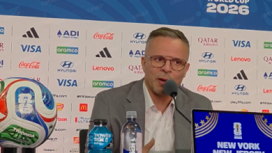 ouahbi-2 | MCG24 | موقع إلكتروني مغربي شامل متجدد على مدار الساعة Man in a suit and glasses speaks into a microphone at a press conference with a World Cup 2026 backdrop and sponsor logos behind him.