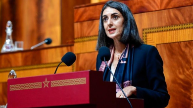 nadia fettah | MCG24 | موقع إلكتروني مغربي شامل متجدد على مدار الساعة Woman in a dark blazer speaks at a red lectern with two microphones in a wood-paneled chamber, likely delivering a formal speech or presentation.
