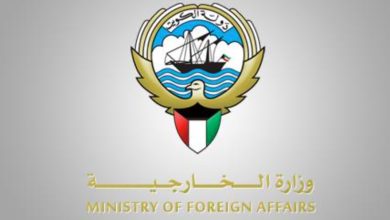Logo of the Ministry of Foreign Affairs with a ship in a blue circle, waves, and a dove, plus a shield colored like the Kuwaiti flag and Arabic text (ministry seal).