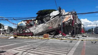 215148484 | MCG24 | موقع إلكتروني مغربي شامل متجدد على مدار الساعة Collapsed building and rubble blocking a city street with yellow caution tape and overhead power lines.",