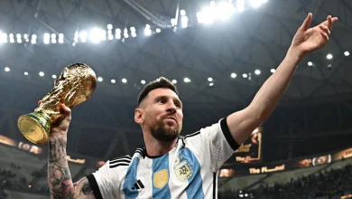 515458 | MCG24 | موقع إلكتروني مغربي شامل متجدد على مدار الساعة Messi in Argentina jersey raises his arm, holding the FIFA World Cup trophy in celebration on a stadium stage
