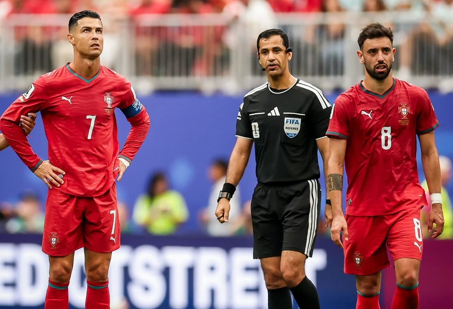 vis_0617202620134388 | MCG24 | موقع إلكتروني مغربي شامل متجدد على مدار الساعة Two Portugal soccer players in red uniforms with numbers 7 and 8 stand beside a FIFA referee on a soccer field.