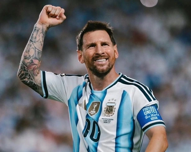 vis_0622202620180715 | MCG24 | موقع إلكتروني مغربي شامل متجدد على مدار الساعة Argentine footballer celebrating on the pitch, fist raised, wearing white-and-light-blue striped jersey with the number 10 and captain armband highlight tattoos on his arm.