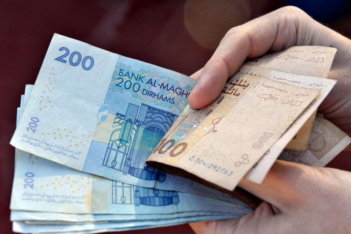أموال-1 | MCG24 | موقع إلكتروني مغربي شامل متجدد على مدار الساعة Hand holding a fan of Moroccan dirham banknotes (200 and 100).