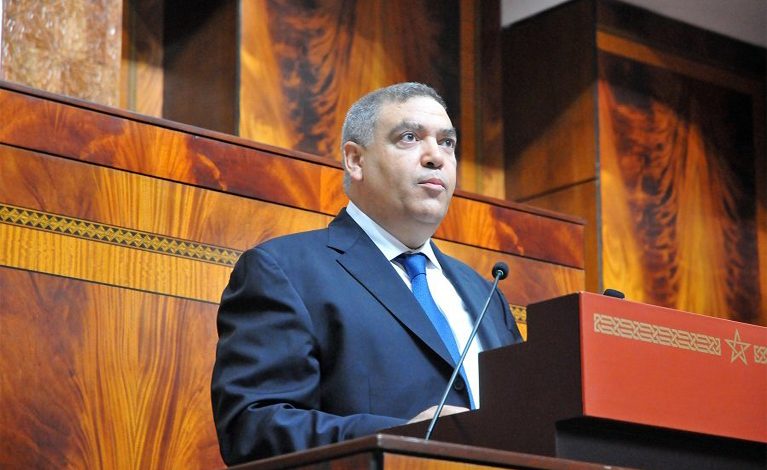 الفتيت | MCG24 | موقع إلكتروني مغربي شامل متجدد على مدار الساعة Man in a dark suit gives a speech at a wooden podium with a microphone in a formal hall
