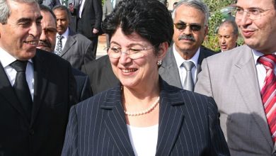 الوزيرة السابقة لطيفة العابدة | MCG24 | موقع إلكتروني مغربي شامل متجدد على مدار الساعة Smiling woman in a navy pinstripe suit and pearl necklace, flanked by men in suits at an outdoor formal event.
