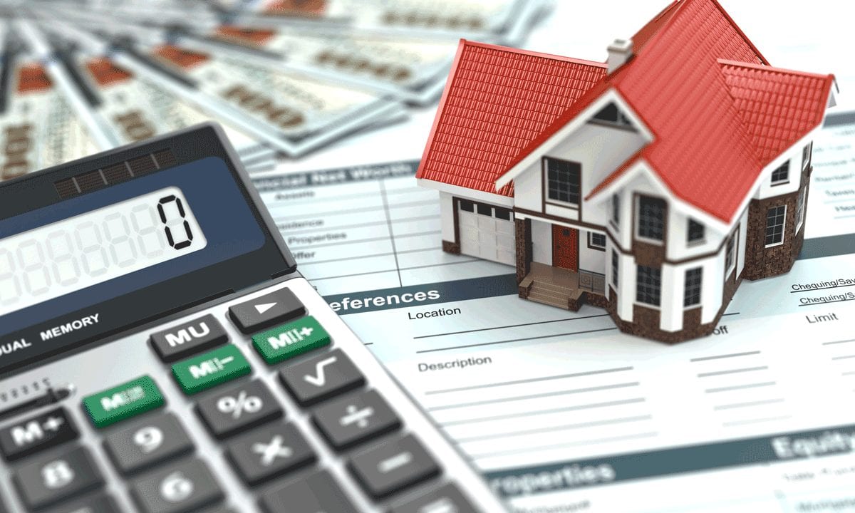 Calculator and a small house model on mortgage documents, illustrating home financing planning