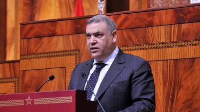لفتيت-202205 | MCG24 | موقع إلكتروني مغربي شامل متجدد على مدار الساعة Man in a dark suit giving a speech at a wooden podium in a formal assembly hall.**