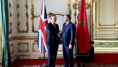 ٧-3 | MCG24 | موقع إلكتروني مغربي شامل متجدد على مدار الساعة Two men in suits shake hands in a gilded room with the UK and Moroccan flags behind them.